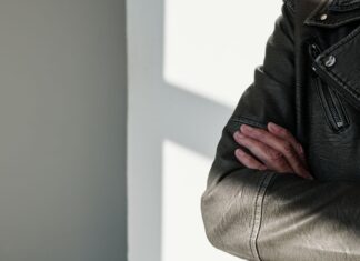 Skrzyżowane ramiona w czarnej skórzanej kurtce w promieniach słońca