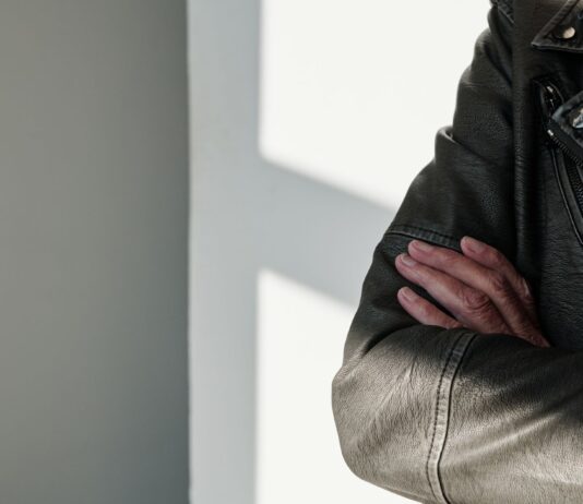 Jak radzić sobie z pękającą skórą na łokciach kurtki – odpowiedzi na wasze problemy Skrzyżowane ramiona w czarnej skórzanej kurtce w promieniach słońca